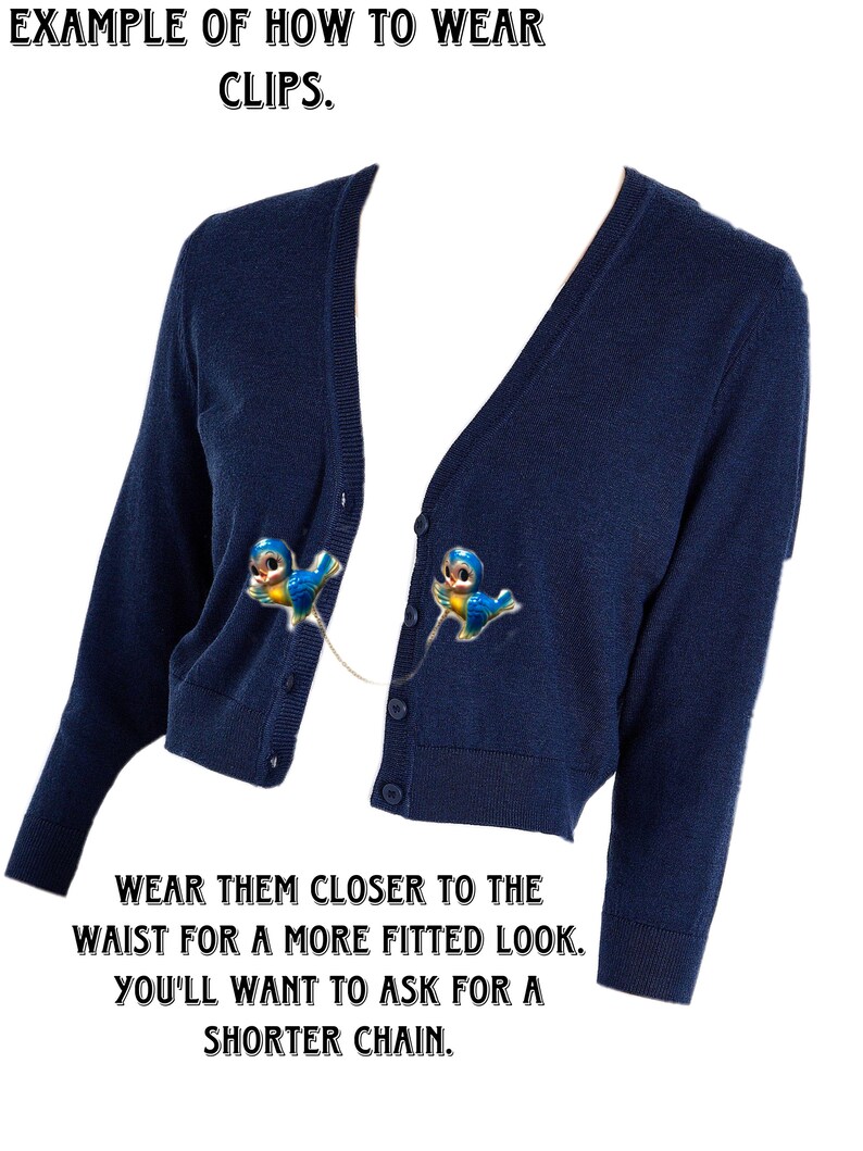 May include: A navy blue cardigan with two blue bird clips attached to the front. The text "EXAMPLE OF HOW TO WEAR CLIPS." is at the top of the image. The text "WEAR THEM CLOSER TO THE WAIST FOR A MORE FITTED LOOK. YOU'LL WANT TO ASK FOR A SHORTER CHAIN." is at the bottom of the image.