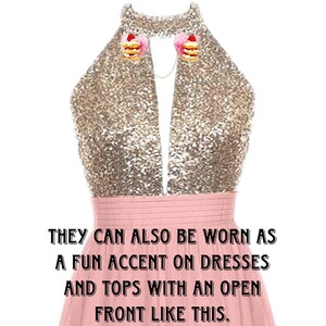 May include: A pink dress with a gold sequined top. The dress has a deep V-neckline and is styled with two small cake-shaped clips on the neckline. The text "EXAMPLE OF HOW TO WEAR CLIPS." is at the top of the image. The text "THEY CAN ALSO BE WORN AS A FUN ACCENT ON DRESSES AND TOPS WITH AN OPEN FRONT LIKE THIS." is at the bottom of the image.