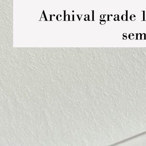 May include: Close-up of white paper with a semi-smooth textured surface. The text "Archival grade 100% Cotton rag / semi-smooth textured surface" is displayed on the paper. The paper has a slight angle.