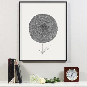 May include: Black and white floral art print in a black frame. The artwork features a detailed, circular flower head with a thin stem and leaf. A white mantel displays books, a small frame, flowers, and a wooden clock.
