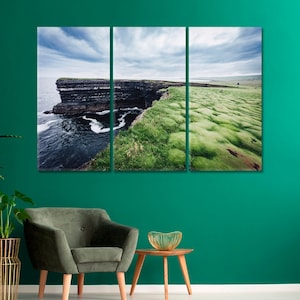 May include: A panoramic view of a rugged cliffside overlooking a choppy ocean. The cliff is covered in lush green grass and the sky is a cloudy blue.
