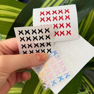 May include: Four sheets of stickers with different designs. The first sheet has black X's, the second sheet has red X's, the third sheet has white X's, and the fourth sheet has pastel colored X's.