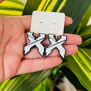 May include: A pair of white and black geometric earrings with silver hooks. The earrings are in the shape of an X. The text "Nocturnal Print Shop" is at the top of the image.