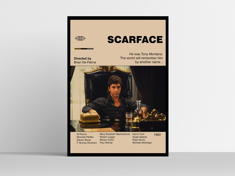 May include: A framed poster for the film "Scarface" featuring Al Pacino. The poster has a tan background with the film title and credits. The image shows Pacino as Tony Montana, seated in a chair. The poster includes the director's name and the year 1983.