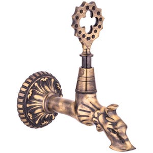 May include: Antique brass-finished faucet with a dragon-head spout and ornate detailing. The faucet features a decorative handle and a round wall mount with floral patterns. A unique fixture for a bathroom or kitchen.