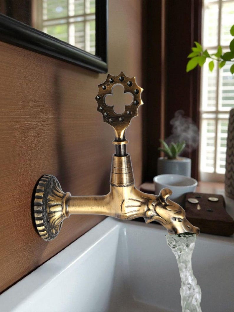 May include: An antique-style faucet with a decorative handle and a dragon-shaped spout. The faucet is made of brass and is mounted on a brown wall. Water flows from the spout into a white sink.