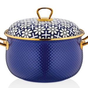 Op de afbeelding: Een blauwe emaille pan met een gouden rand en handvatten. De deksel heeft een wit en zwart geometrisch patroon.
