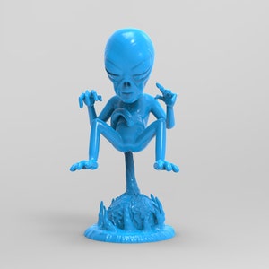 Puede incluir: Una figurita de extraterrestre azul con tres dedos en cada mano, de pie sobre una base azul con un diseño de llama. El extraterrestre tiene una cabeza grande y está en posición sentada con las piernas cruzadas.