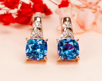 Peut inclure: Une paire de boucles d'oreilles en or avec des accents de pierres précieuses bleues. Chaque boucle d'oreille présente une pierre précieuse bleue de forme carrée entourée d'un halo de petites pierres précieuses claires. Les boucles d'oreilles ont un design simple et élégant.
