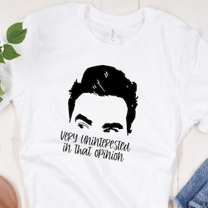 May include: White t-shirt with a black silhouette of a man's face and the text "Very Uninterested in That Opinion".