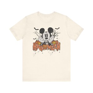 May include: A white t-shirt with a vintage-style graphic of Mickey Mouse dressed as a skeleton with pumpkins and the text "HALLOWEEN".