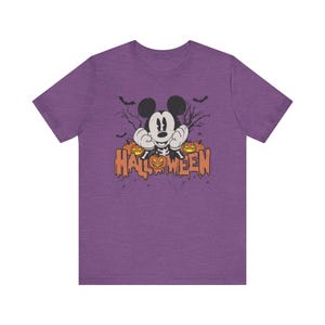 May include: Purple t-shirt with a vintage-style image of Mickey Mouse dressed as a skeleton with pumpkins and the text "HALLOWEEN".