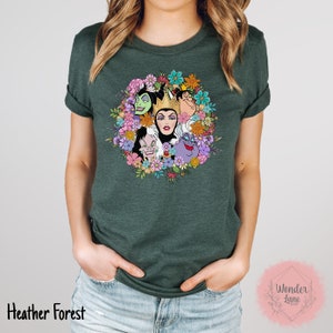 May include: A green t-shirt with a floral design featuring the faces of Disney villains, including Maleficent, Cruella de Vil, Ursula, and the Evil Queen. The design is surrounded by colorful flowers.