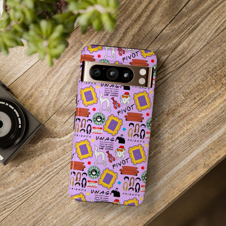 May include: A purple phone case with a repeating pattern of iconic images and phrases from the TV show Friends. The case features the Central Perk logo, the iconic orange couch, the phrase "Pivot", and the characters' names.