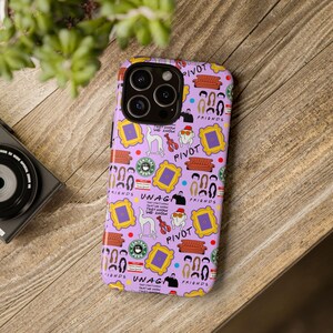 May include: Purple phone case with a pattern of Friends TV show characters, logos, and quotes. The case features the iconic orange couch, the Central Perk logo, and the phrase "Pivot!"