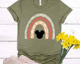 May include: A green t-shirt with a rainbow design and the text "stay wild". A black Mickey Mouse silhouette is in the center of the rainbow.