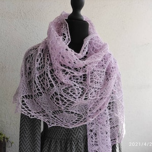 Może przedstawiać: Delikatny, jasnolilawy szal z koronki, drapowany na manekinie. Szal wykonany jest z cienkiej, misternej koronki i ma delikatny, kobiecy wygląd.