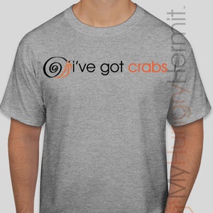 May include: A heather gray short-sleeved t-shirt featuring a black spiral graphic and the text "I've got crabs" printed in black and orange lettering across the chest. The design includes a small orange crab illustration integrated with the spiral.
