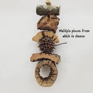 May include: A hanging ornament composed of natural wood and bark segments, including a spiky seed pod and a circular bark ring. The text "Multiple pieces from which to choose" is visible, along with the brand name "Crabitanurals" and website.