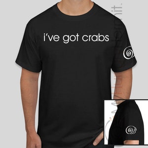 May include: Black t-shirt with white text that reads "i've got crabs". The shirt has a white snail design on the right sleeve.