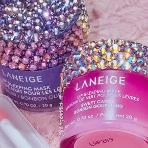 Könnte beinhalten: Zwei Laneige Lip Sleeping Mask. Eines ist lila mit einem kristallbesetzten Deckel, das andere ist rosa mit einem kristallbesetzten Deckel. Die rosa Maske ist mit "Sweet Candy" beschriftet, Nettogewicht 20 g.