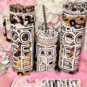 May include: Three stainless steel tumblers with a brown and white marble design and a black and white "COFFEE" graphic. The tumblers have a clear lid and a straw. The tumblers are sitting on a pink fluffy surface.