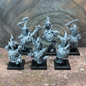May include: A set of six unpainted grey plastic miniature figures featuring goblin-like creatures with pointed hoods riding on top of round, toothy, spherical monsters. Each figure is mounted on a square black base, with various weapons.