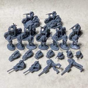 Puede incluir: Un conjunto de figuras en miniatura de plástico gris de soldados que montan motocicletas y sidecars. Algunas figuras sostienen armas, mientras que otras sostienen herramientas. También hay varias figuras más pequeñas de soldados tumbados o sentados.