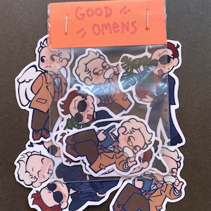 May include: A set of Good Omens stickers featuring various characters from the book and TV series. The stickers are colorful and feature a variety of expressions.