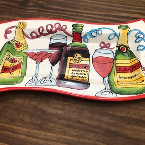 May include: A white ceramic serving tray with a red rim, featuring a colorful illustration of wine bottles and glasses. The tray has a wavy edge and is decorated with a whimsical design of red, blue, and yellow swirls.