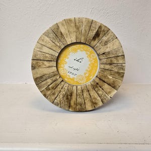 May include: A round picture frame made of bone with a yellow background and the text "ihr seid 13+31.5" in the center.