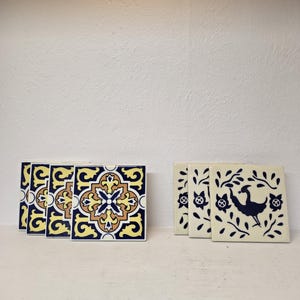 May include: Five ceramic tiles with a blue and yellow geometric pattern and three ceramic tiles with a white background and a black silhouette of a bird with floral accents.