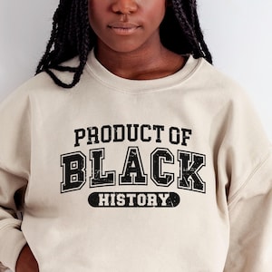 May include: A beige sweatshirt with black text that reads "PRODUCT OF BLACK HISTORY".