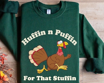 May include: A dark green sweatshirt featuring the text "Huffin n Puffin" and a cartoon turkey illustration. Below the turkey is the text "For That Stuffin". The turkey is brown, yellow, red, and white.
