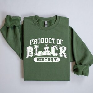 May include: A green sweatshirt with white text that reads "Product of Black History".