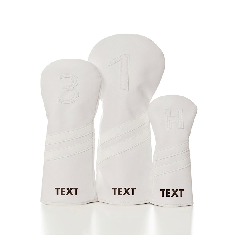 May include: Set of three white golf headcovers with black embroidered numbers 1, 3, and H. The headcovers have black embroidered text that says "TEXT" on each.