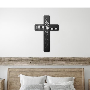 Può includere: Un letto con struttura in legno con un copriletto bianco e due cuscini. Il letto è in una camera da letto con una testiera in legno e una croce in metallo nero con note musicali su di essa appesa al muro. Ci sono due comodini in legno con lampade sopra e due cesti di vimini sul pavimento davanti al letto.