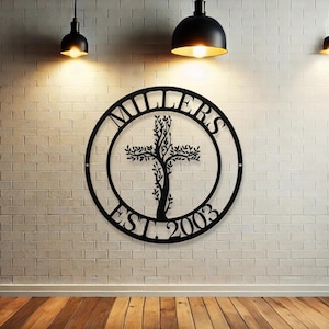 Puede incluir: Decoración de pared de metal negro con un diseño circular que presenta un árbol que crece en una cruz. El círculo tiene el texto "MILLERS EST 2003" alrededor del borde.