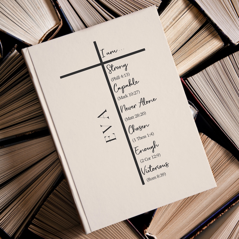 Op de afbeelding: Een wit boek met de naam "EVA" verticaal geschreven aan de linkerkant. Aan de rechterkant van het boek is een zwart kruis getekend met de woorden "Ik ben..." bovenaan het kruis. De woorden "Sterk, Bekwaam, Nooit alleen, Uitverkoren, Genoeg, Overwinnend" staan op het kruis geschreven met bijbelverzen tussen haakjes naast elk woord.