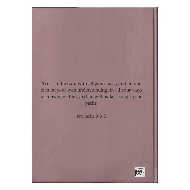 Op de afbeelding: Een roze boek met de tekst "Trust in the Lord with all your heart, and do not lean on your own understanding. In all your ways acknowledge him, and he will make straight your paths. Proverbs 3:5-6" gedrukt op de omslag.