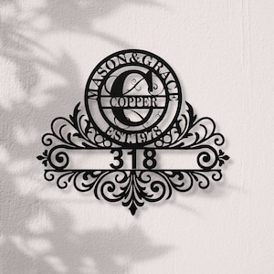 Könnte beinhalten: Schwarzes Hausnummernschild aus Metall mit einem dekorativen Schnörkeldesign. Das Schild zeigt einen Kreis mit dem Text "MASON & GRACE" und dem Buchstaben "C" darin. Der Text "COPPER EST 1978" ist ebenfalls enthalten. Die Hausnummer "318" ist auf dem Schild angezeigt.