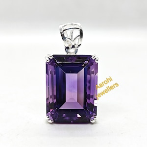 May include: A rectangular, faceted amethyst pendant with a silver bail. The deep purple gemstone is set in a silver frame. The pendant is a striking piece of jewellery, perfect for adding a touch of elegance to any outfit.