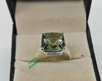 May include: A silver ring with a large, square-shaped green gemstone. The ring is in a black and white ring box.