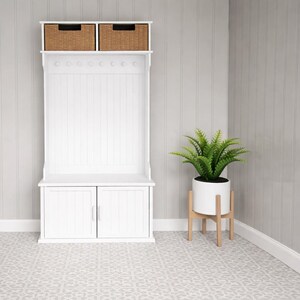 May include: A white hall tree with two woven baskets, a row of hooks, and a cabinet with two doors. A potted plant in a white pot sits on a wooden stand. The floor has a patterned design.