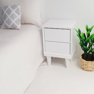 May include: White bedside table with two drawers and four legs. The table is made of wood and has a simple design.