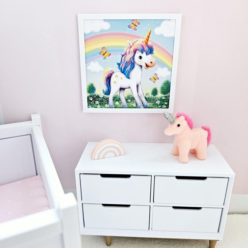 Pode incluir: Uma c&oacute;moda branca com seis gavetas, um brinquedo de peluche de unic&oacute;rnio rosa e uma decora&ccedil;&atilde;o de arco-&iacute;ris de madeira colorida. Uma imagem emoldurada de um unic&oacute;rnio de p&eacute; num campo com um arco-&iacute;ris acima dele pendura na parede atr&aacute;s da c&oacute;moda.
