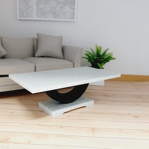 May include: White coffee table with a black, curved base. The table top has a speckled finish.