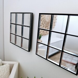 May include: Two black framed mirrors with a grid pattern. The larger mirror is on the right and the smaller mirror is on the left.