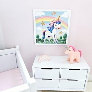 Pode incluir: Uma imagem enquadrada branca de um unic&oacute;rnio com um arco-&iacute;ris e borboletas. Um brinquedo de pel&uacute;cia rosa em forma de unic&oacute;rnio est&aacute; sentado em uma c&ocirc;moda branca com quatro gavetas. Uma decora&ccedil;&atilde;o de madeira em forma de arco-&iacute;ris est&aacute; sentada na c&ocirc;moda.