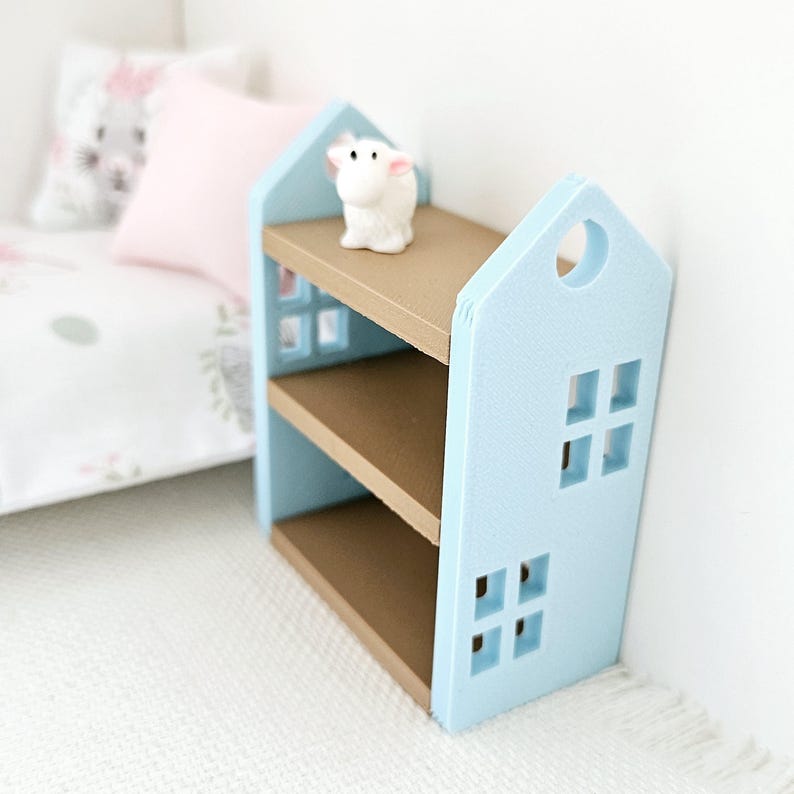 May include: A light blue bookshelf shaped like a house with two shelves and brown shelves. A small white figurine is on the top shelf.